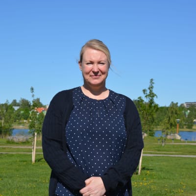 Tatjana Asplund står i en park. I bakgrunden syns vatten och höghus bland träden.