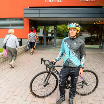 En man med cykel som står framför simhallen.