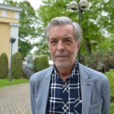 En man med rutig skjorta och grått hår.