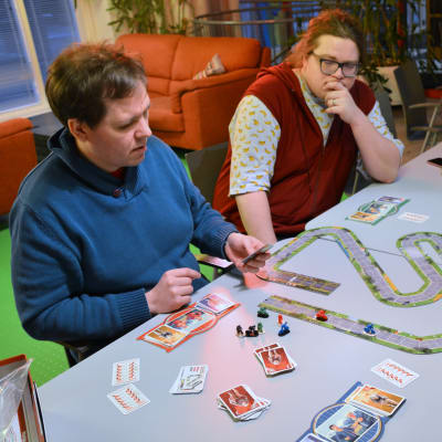 Personer spelar brädspel kring ett långbord.