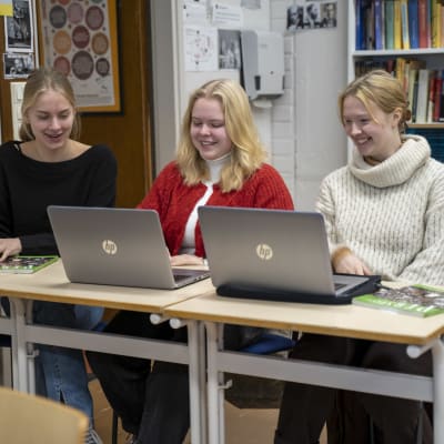 Tre gymnasieelever framför datorer.