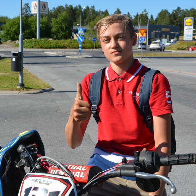 En 16-årig pojke sitter på en moped och visar tummen upp.