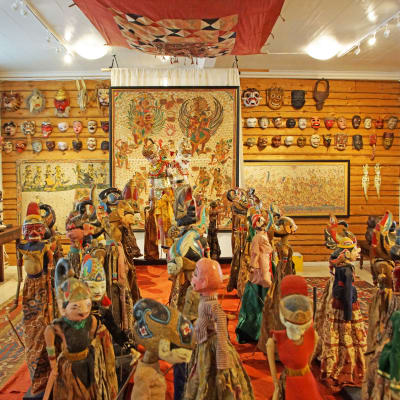 konstutställning med ett rum fyllt av tavlor och dockor och masker