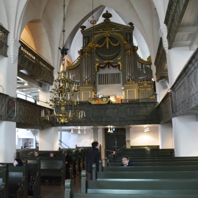 Medeltida kyrka med mörkgröna bänkar.