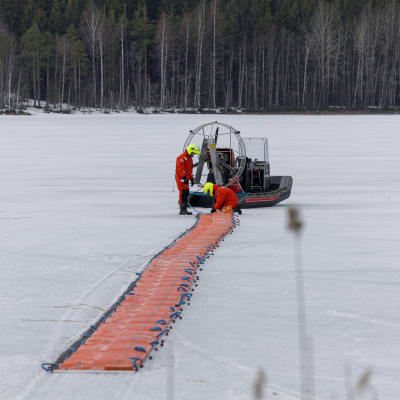 Pelastulaitoksen työntekijät siirtävät öljyntorjuntapuomia ilmatyynyaluksella jäällä Viljakanlahdella Joutsenossa.
