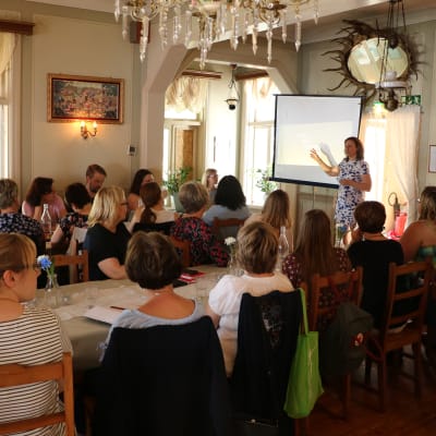 Ett tjugotal personer följer med en presentation i en restaurang.