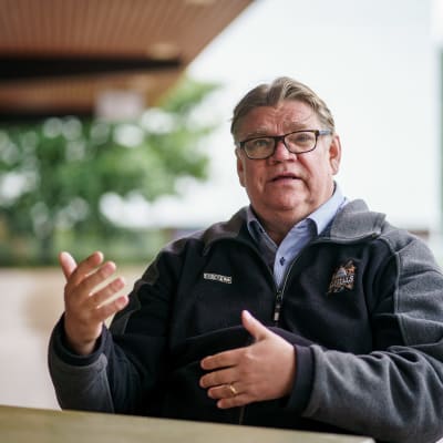 Timo Soini puhuu käsillään terassin pöydässä.
