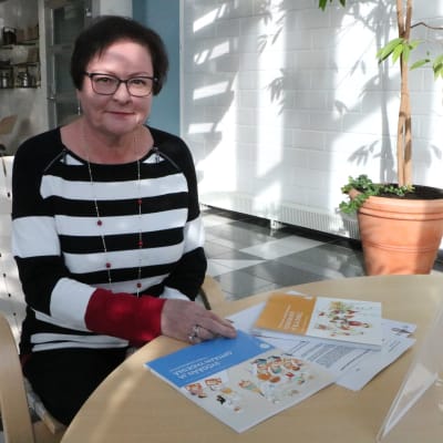 Kvinna med randig tröja sitter vid et bord.