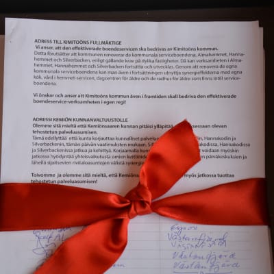 Rött silkesband runt hög med papper.