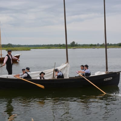 Postrodden, män som ror en träbåt i gammal stil.