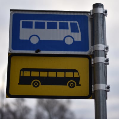 Bussipysäkin kyltti, yllä sinisellä pohjalla valkoinen bussi. Alla keltaisella pohjalla musta bussi.