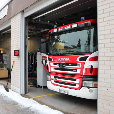 En brandstation med en av garageportarna öppna med en brandbil parkerad i hallen. 