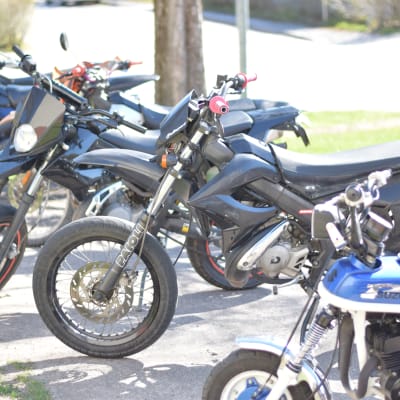 Mopeder parkerade i en rad.De råkar alla vara blå.