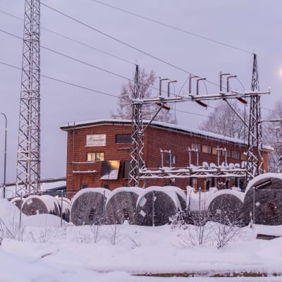 Tegelhus bland elstolpar i snöigt landskap. 