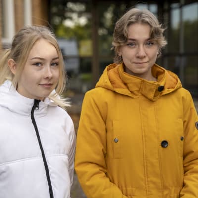 Två personer står framför Ekenäs gymnasium.