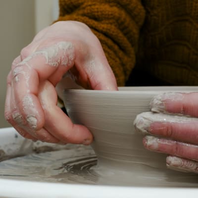 Händer som drejar en skål av lera. 