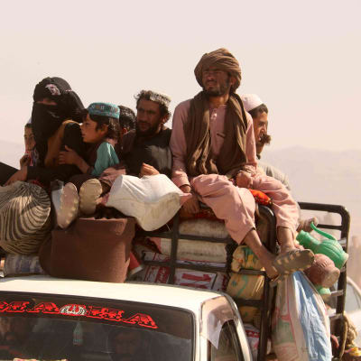 Flyktingar från Afghanistan sitter på taket av en fullpackad bil.