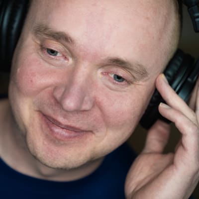 Petri Poikolainen lähikuvassa kuuntelee musiikkia luurit päässä.