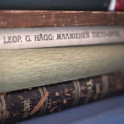Tre gamla böcker på hög, varav den översta är skriven av Leopold G. Hägg och heter "Maamiehen tieto-opas". 