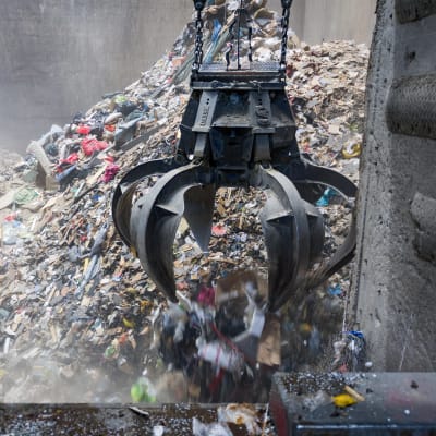 Vantaan jätteenpolttolaitoksen poltettavaksi kasattua jätettä varastoaltaassa ja sen käsittelyyn tarvittava nostokoura.