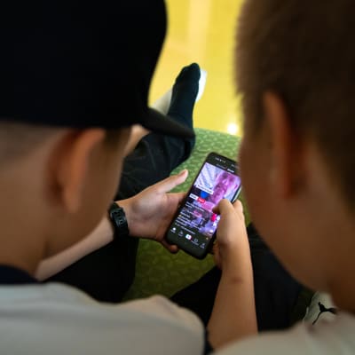 Barn som håller i en mobiltelefon och tittar på en video på Tiktok.