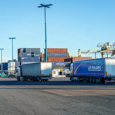 Tre lastbilar i ett hamnområde.