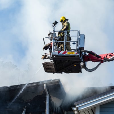 En brandman i skylift släcker ett brinnande hus