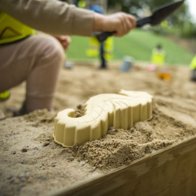 Barn gör sandkakor i en sandlåda. 