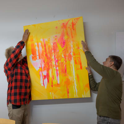 Hämeenlinnalainen taiteilija Chingiz Abassov (vas.) ja Aarne Arponeva asettavat taideteosta seinälle.