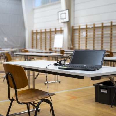 En stol vid ett bord där det finns en bärbar dator under studentskrivningar.