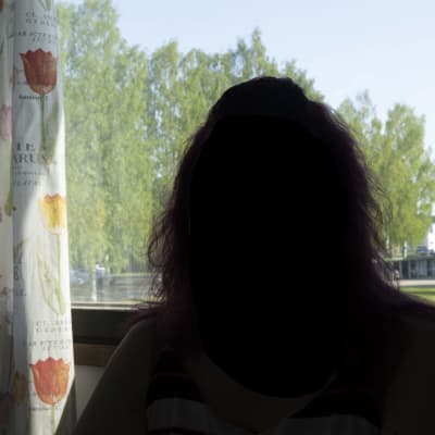 Ihminen tummana ikkunaa vasten.