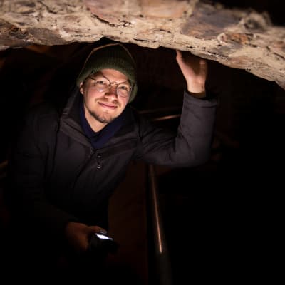 Arkeologi Ilari Aalto taskulampun valossa Turun tuomiokirkon ullakolla holvikaaren alla.
