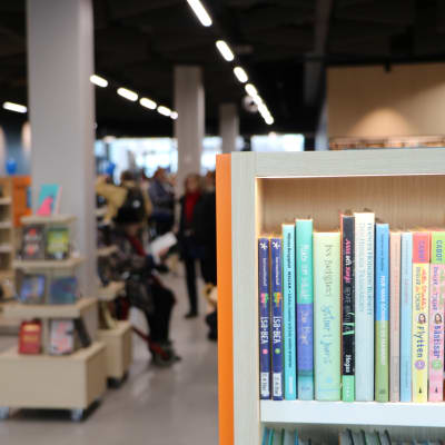 En bokhylla i Degerö bibliotek med suddig bakgrund. 