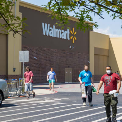 Människor med ansiktsskydd promenerar bort från en Walmart-butik