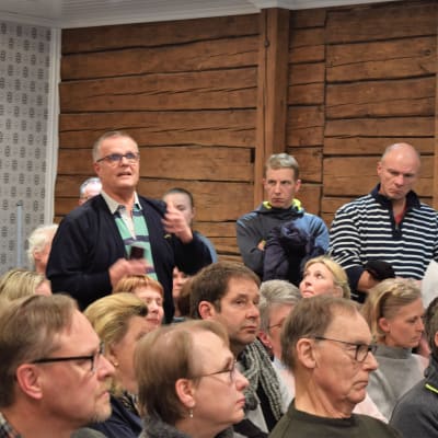En skara människor i Wlhelmsdal i Ingå. En man står upp och ställer en fråga. 