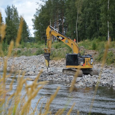 En grävmaskin vid en å.
