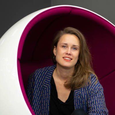 Eva-Maria Koskinen poserar i rund bollstol i Yles aula.