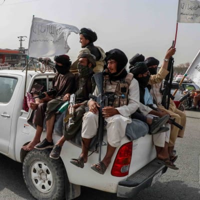 Joukko taliban-taistelijoita valkoisen avolava-auton lavalla 17. elokuuta 2021.