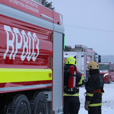 Två brandmän står intill en brandbil. I bakgrunden skymtar en till brandbil.
