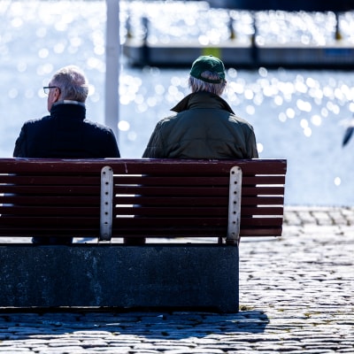 Kaksi henkilö istuu penkillä Helsingin kauppatorilla.