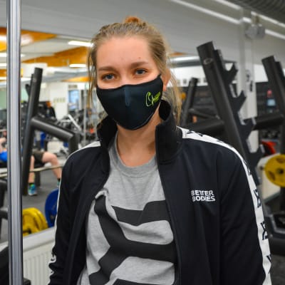 Ung kvinna med munskydd i ett gym.