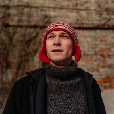 Näyttelijä Juri Borisov katsoo ylöspäin, taustalla tiiliseinä.
