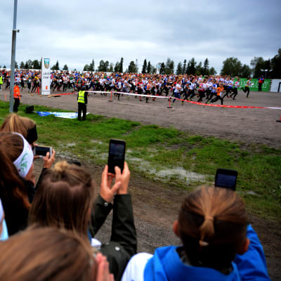 Yleisö katsoo, kun iso määrä suunnistajia lähtee juoksemaan