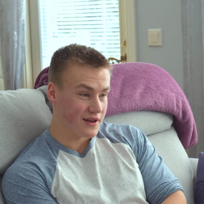 Robin Järviö sitter på en soffa framför ett fönster.