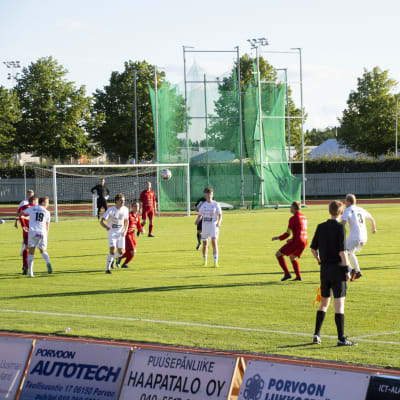 Fotbollsmatch på gräsplan. Ena laget spelar i vita tröjor, det andra i röda.