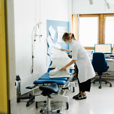 Sjukvårdare ordnar med skyddspapper på en mottagningsstol.