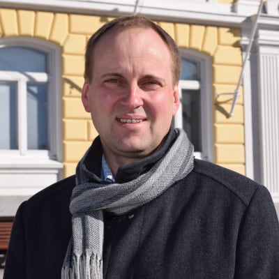 En man i halsduk och jacka står utanför stadshuset i Ekenäs. Raseborgs stadsdirektör Tom Simola.