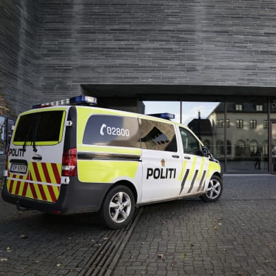 Norsk polisbild framför grå byggnad.