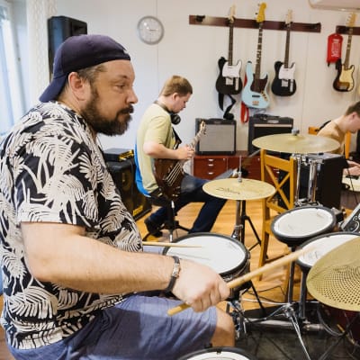 Etalalla  Marlo Paumo paukuttaa rumpuja, taustalla muita Resonaarigroupin muusikoita soittamassa.