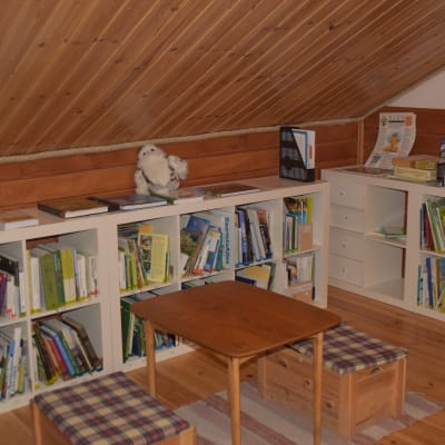 litet bibliotek i naturum med böcker och ett litet bord och stolar